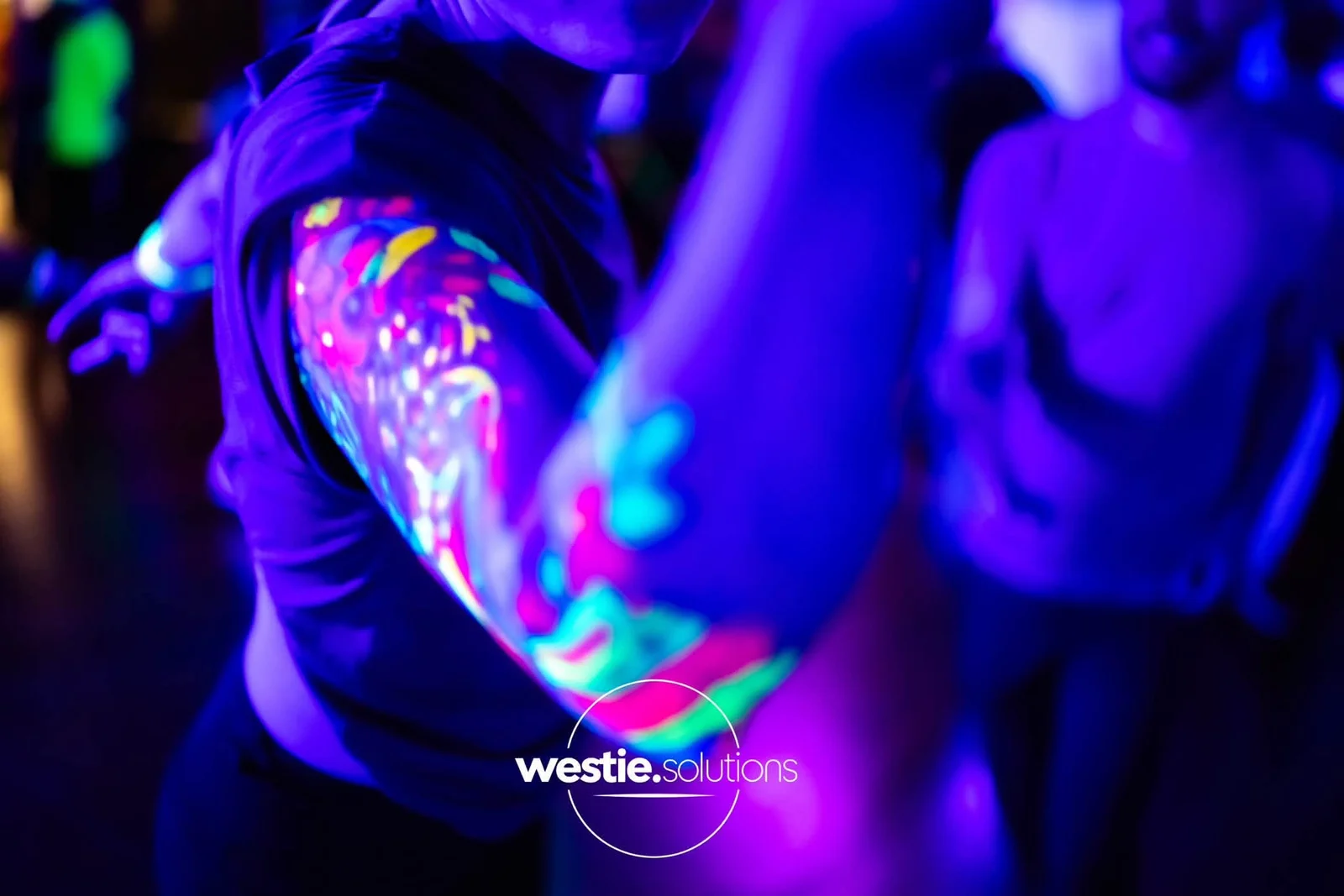 Bunte fluoreszierende Körperbemalung leuchtet während des Tanzens im UV-Licht