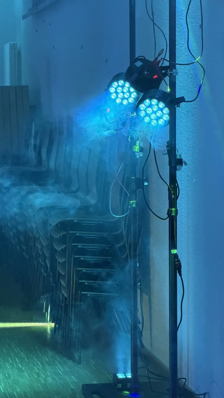 Blaue PAR-Lichter am Stativ und ein Uplight am Boden, deren Licht im Dunst sichtbar wird